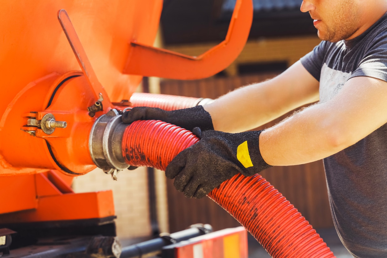 a man connects a suction hose to a tanker truck. Sewage pumping machine. Septic tank. Pumping wastewater from a septic tank. Septic Tank Maintenance Red tube inside septic tank, demonstrating the process of expert septic pumping